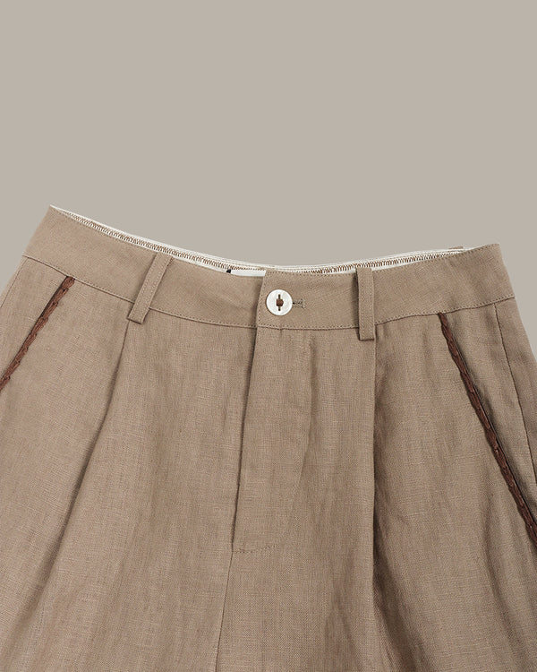 Close-up of brown pants with a button on a beige background