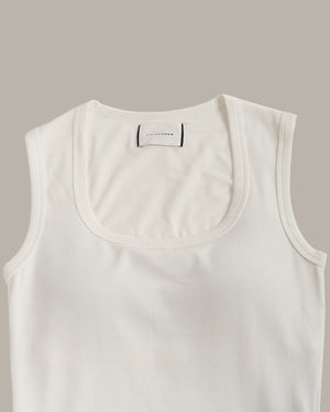 White tank top with a brand label on a beige background