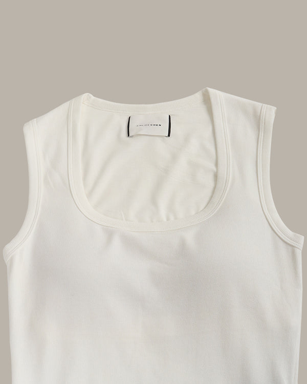White tank top with a brand label on a beige background
