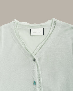 Light blue cardigan with brand label on a gray background