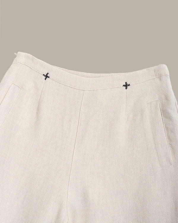 Close-up of beige pants with decorative buttons on a gray background