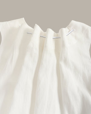 Close-up of a white sleeveless top with subtle stitching detail on a neutral background