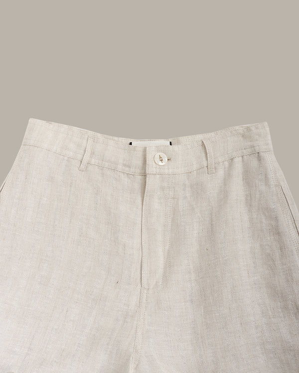 Close-up of beige pants with a button on a neutral background