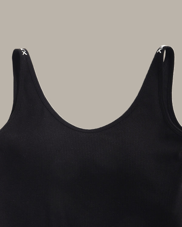 Black tank top with thin straps on a beige background