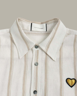 Close-up of a shirt with a heart-shaped patch and 'Chloé' label on a neutral background