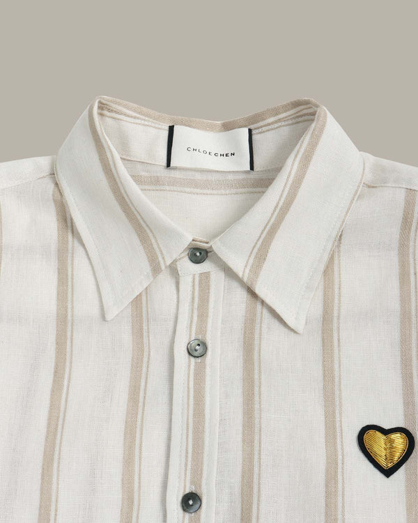 Close-up of a shirt with a heart-shaped patch and 'Chloé' label on a neutral background