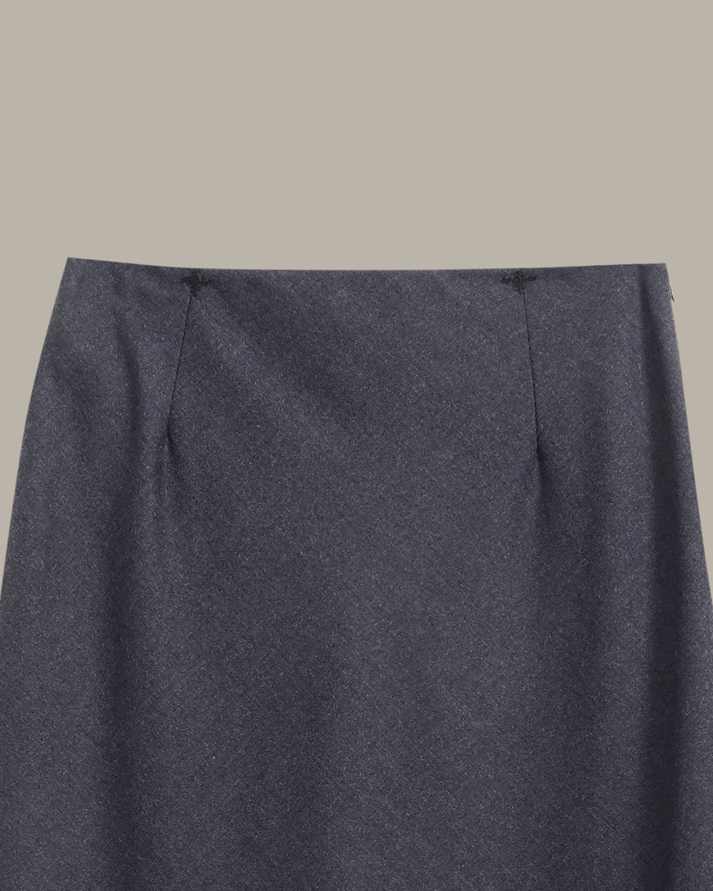 A dark charcoal gray knit midi skirt with a subtle textured pattern, shown flat against a solid taupe-gray background.