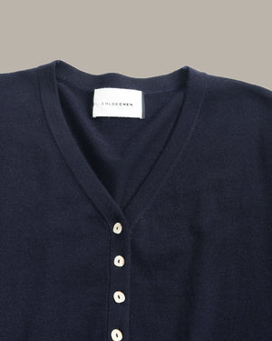 Close-up of a dark navy blue V-neck knit top by Chloé, featuring a white button placket and a white brand label at the collar.