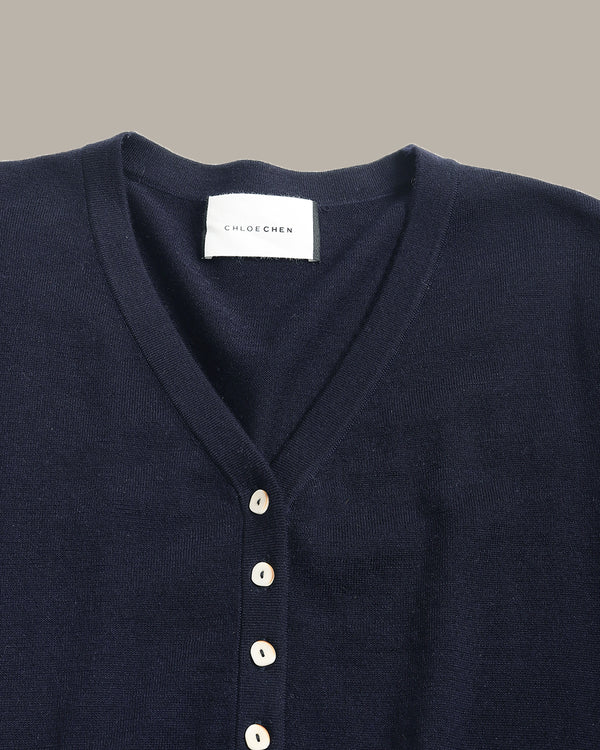 Close-up of a dark navy blue V-neck knit top by Chloé, featuring a white button placket and a white brand label at the collar.