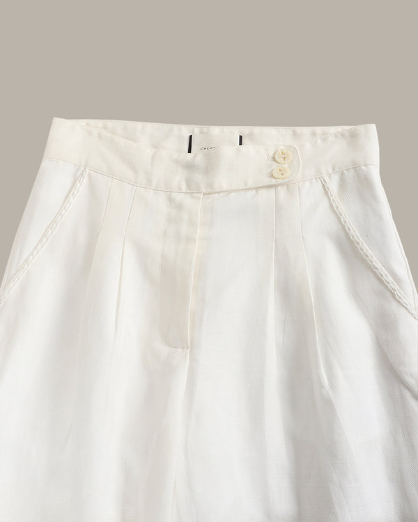 Close-up of a white pants with a button and zipper on a light gray background