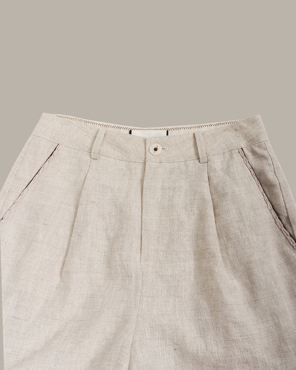 Beige pleated pants on a light gray background