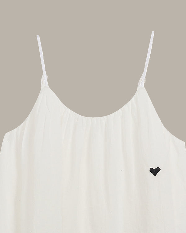 White spaghetti strap top with a black heart detail on a neutral background