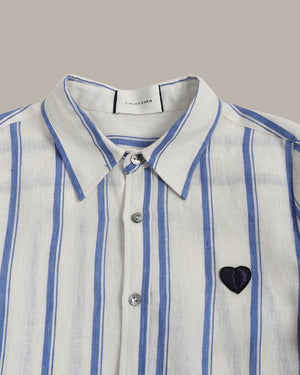White shirt with blue stripes and a blue heart emblem on a gray background