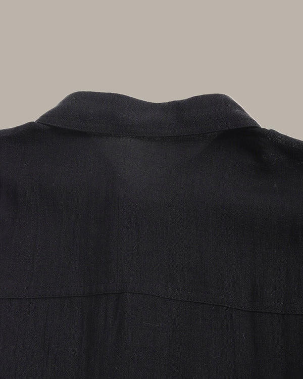 Close-up of a black shirt collar on a neutral background