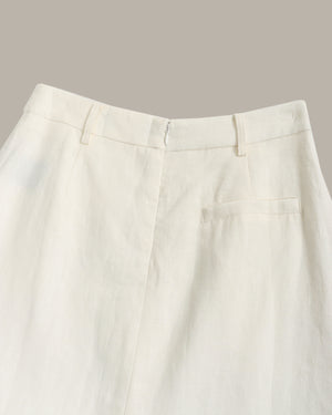 Close-up of the waistband and front of a pair of off-white trousers, showing belt loops, a front fly, and a side welt pocket against a plain taupe background.