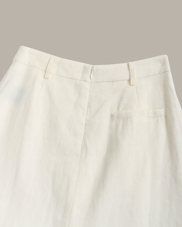Close-up of the waistband and front of a pair of off-white trousers, showing belt loops, a front fly, and a side welt pocket against a plain taupe background.