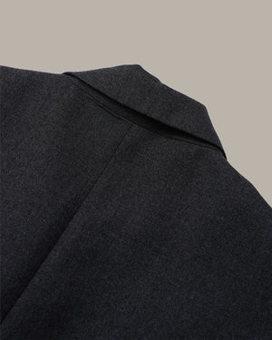 Close-up detail shot of a dark charcoal gray wool coat collar against a solid beige background.