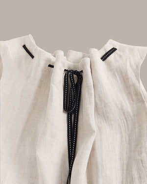 Close-up of a white garment with black drawstrings on a neutral background