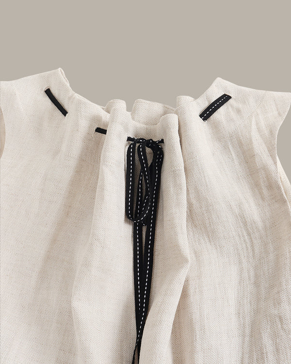 Close-up of a white garment with black drawstrings on a neutral background