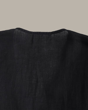 back of a black ruffle blouse with ruffled details on a beige background