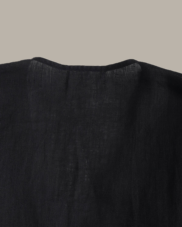 back of a black ruffle blouse with ruffled details on a beige background