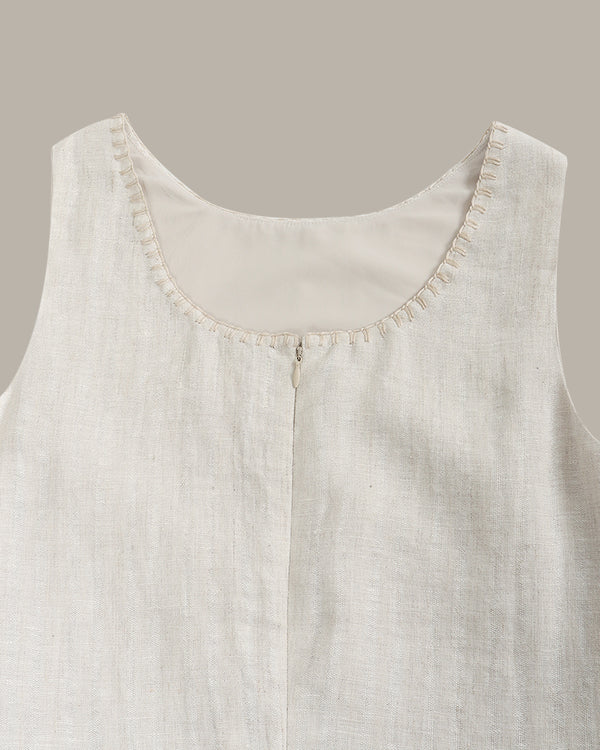 Close-up of a light gray sleeveless garment with textured fabric and visible stitching on a neutral background.