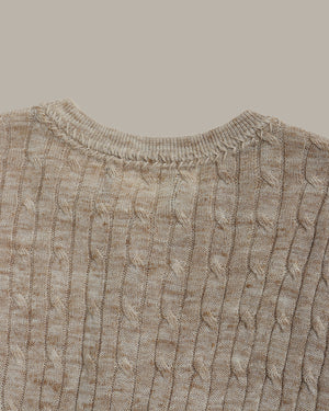 Close-up of a camel cable knit sweater on a light gray background