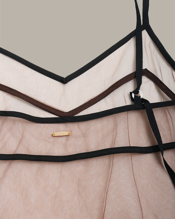 Close-up of a brown sheer mesh cami with black straps and a gold tag on a neutral background