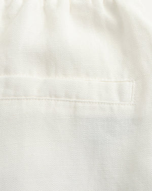 Close-up of a white textured fabric with a stitched pocket detail.