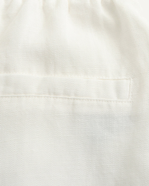 Close-up of a white textured fabric with a stitched pocket detail.