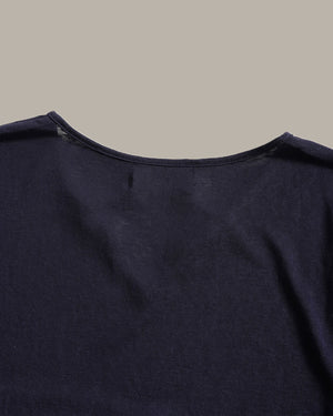 Close-up of the back neckline of a dark navy blue knit top against a solid light gray background.