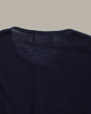 Close-up of a dark navy knit garment, showing the inner neck lining and collar area against a solid taupe background.