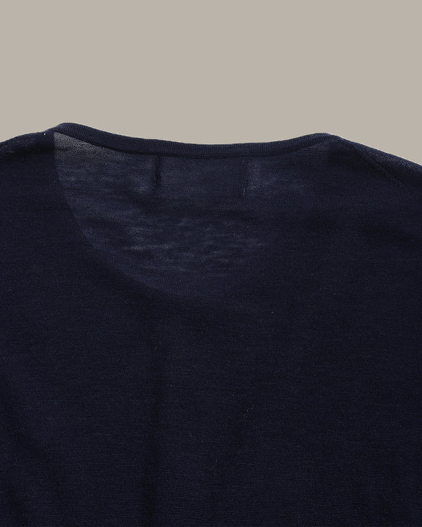 Close-up of a dark navy knit garment, showing the inner neck lining and collar area against a solid taupe background.