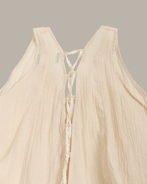 Beige sleeveless top with criss-cross straps on a neutral background