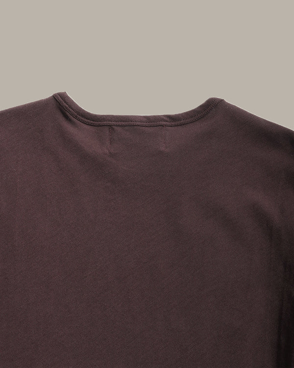 Close-up of a dark brown crew-neck t-shirt showing the collar and upper chest fabric against a solid light gray background.