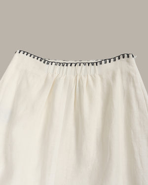 White skirt with black trim on a gray background