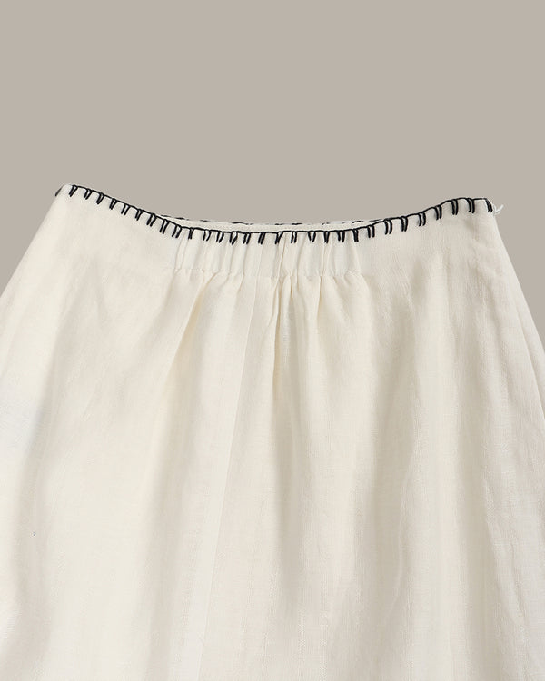 White skirt with black trim on a gray background