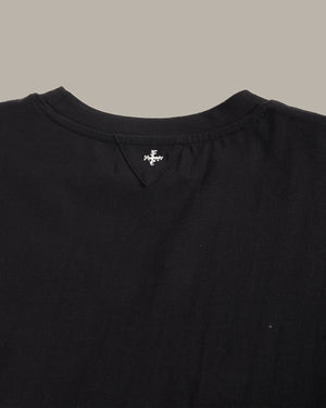Close-up of a black garment with a brand logo on a neutral background