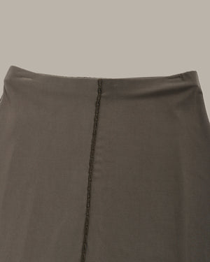 Close-up of a olive green skirt with a visible seam on a neutral background