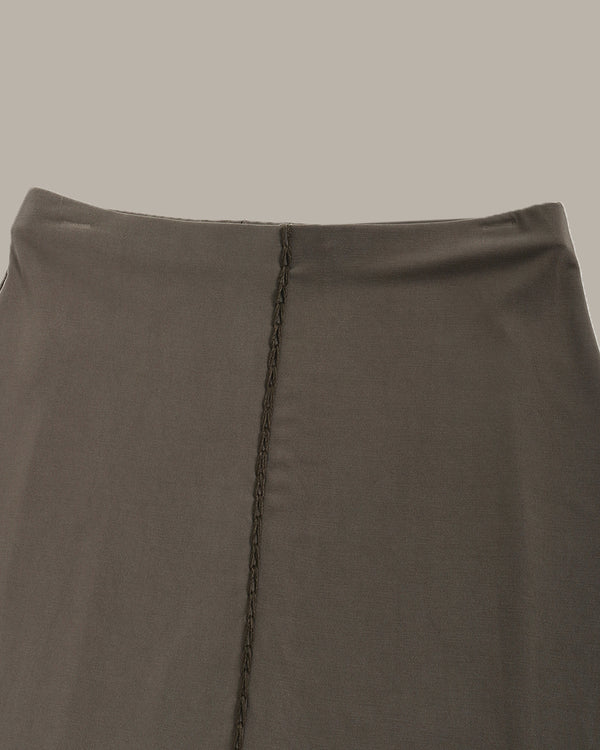 Close-up of a olive green skirt with a visible seam on a neutral background