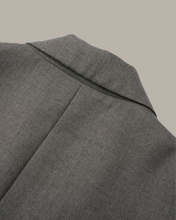 Close-up detail shot of a gray textured fabric jacket, showing the lapel and shoulder seam against a solid neutral background.