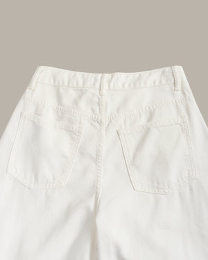 Close-up back view of off-white denim jeans showing the waistband, belt loops, and two back patch pockets against a solid taupe background.