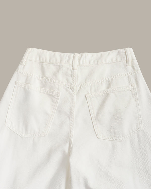 Close-up back view of off-white denim jeans showing the waistband, belt loops, and two back patch pockets against a solid taupe background.
