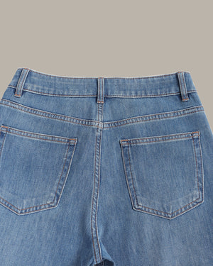 Close-up back view of light blue denim jeans showing the waistband, belt loops, and back pockets against a solid beige background.