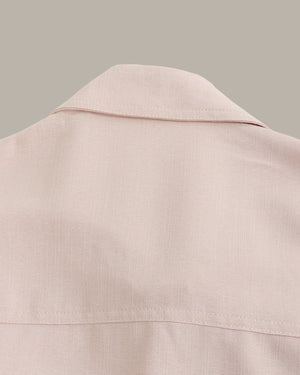 Close-up of a light pink jacket collar on a neutral background