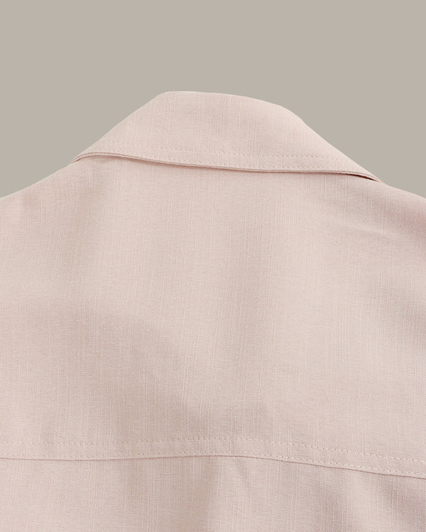 Close-up of a light pink jacket collar on a neutral background