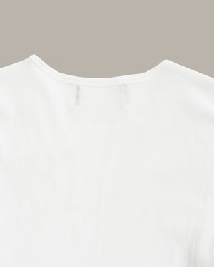 Close-up of the back neckline of a plain white short-sleeve top against a solid taupe background.