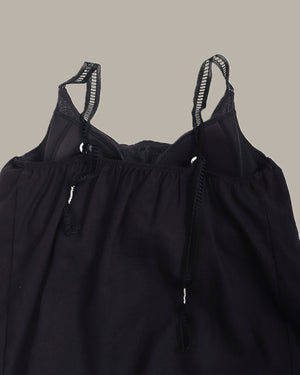 Black top with thin straps on a neutral background
