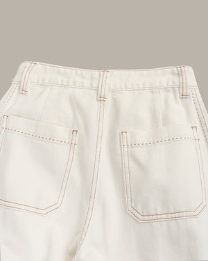 Close-up of light-colored pants with stitching details on a gray background