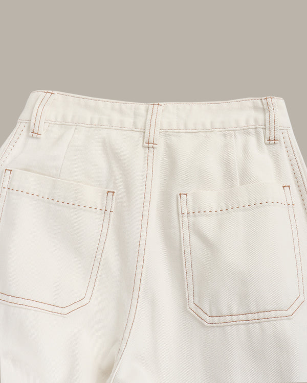 Close-up of light-colored pants with stitching details on a gray background